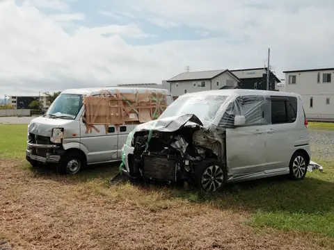 Two wrecked silver vans with crushed fronts standing on a grass verge after a collision
