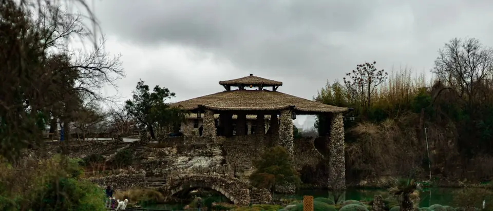 The stone pavilion of the Japanese Tea Garden in San Antonio above its pond and gardens on a cloudy day